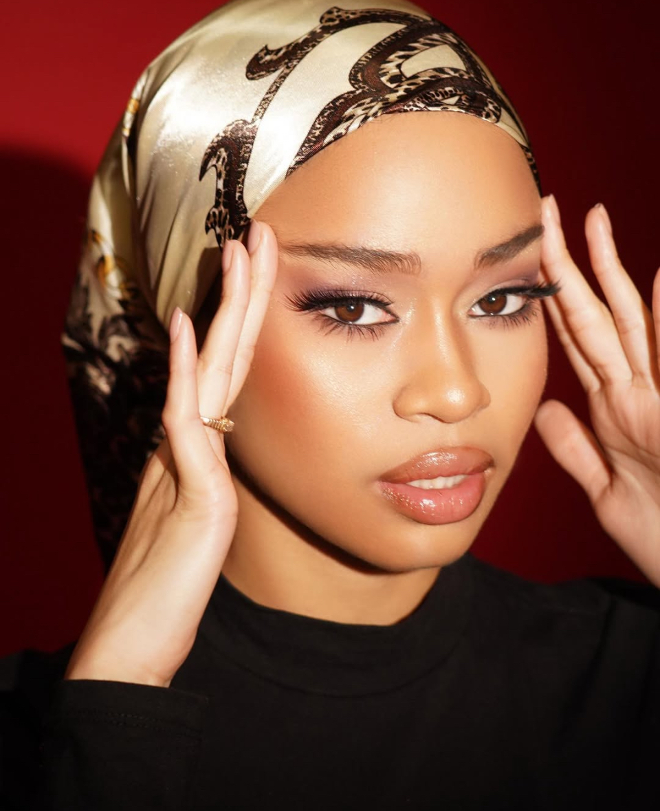 Beauty portrait of a woman in a patterned satin headscarf against a red backdrop