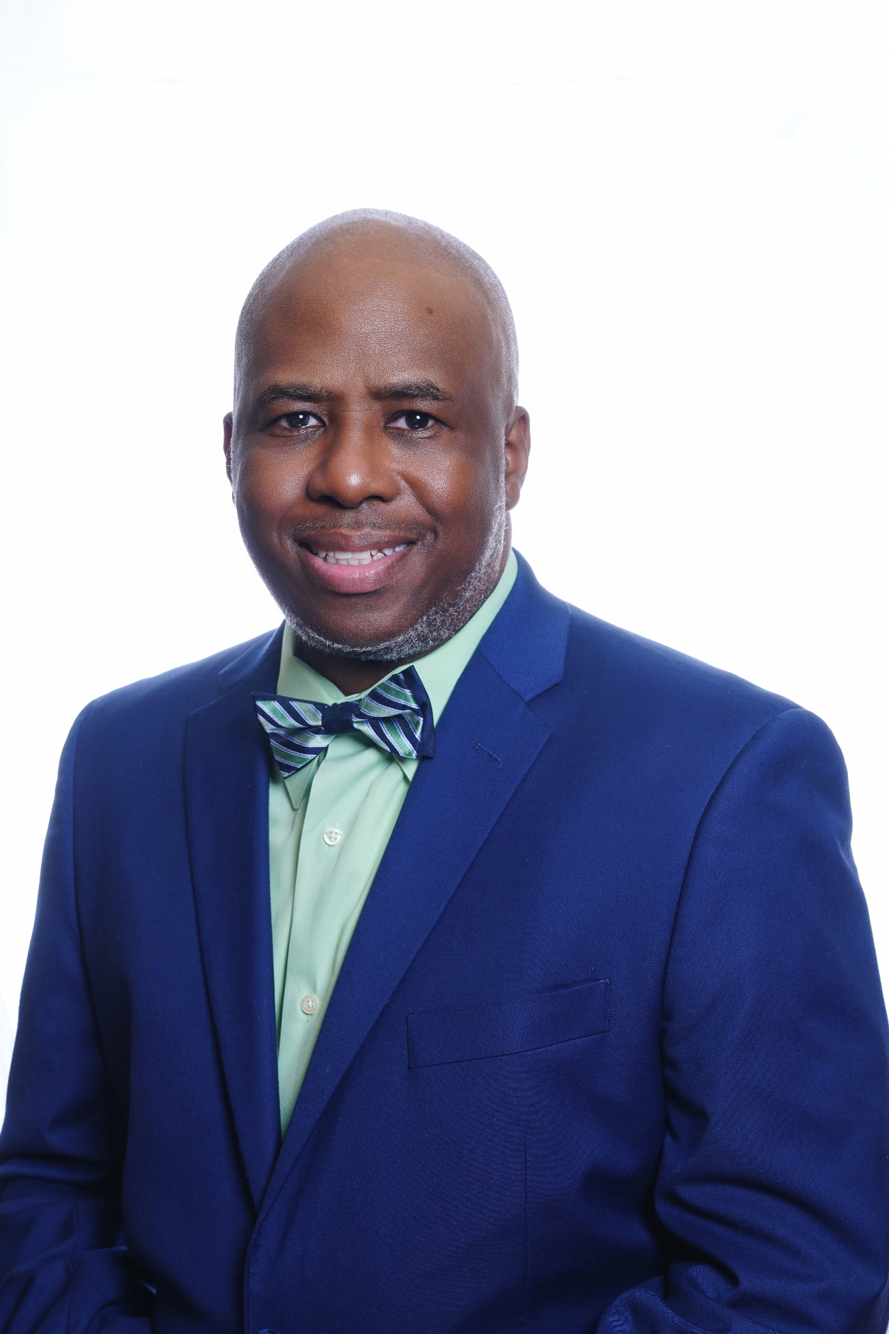Business portrait of a man in a blue suit and bow tie against a bright background