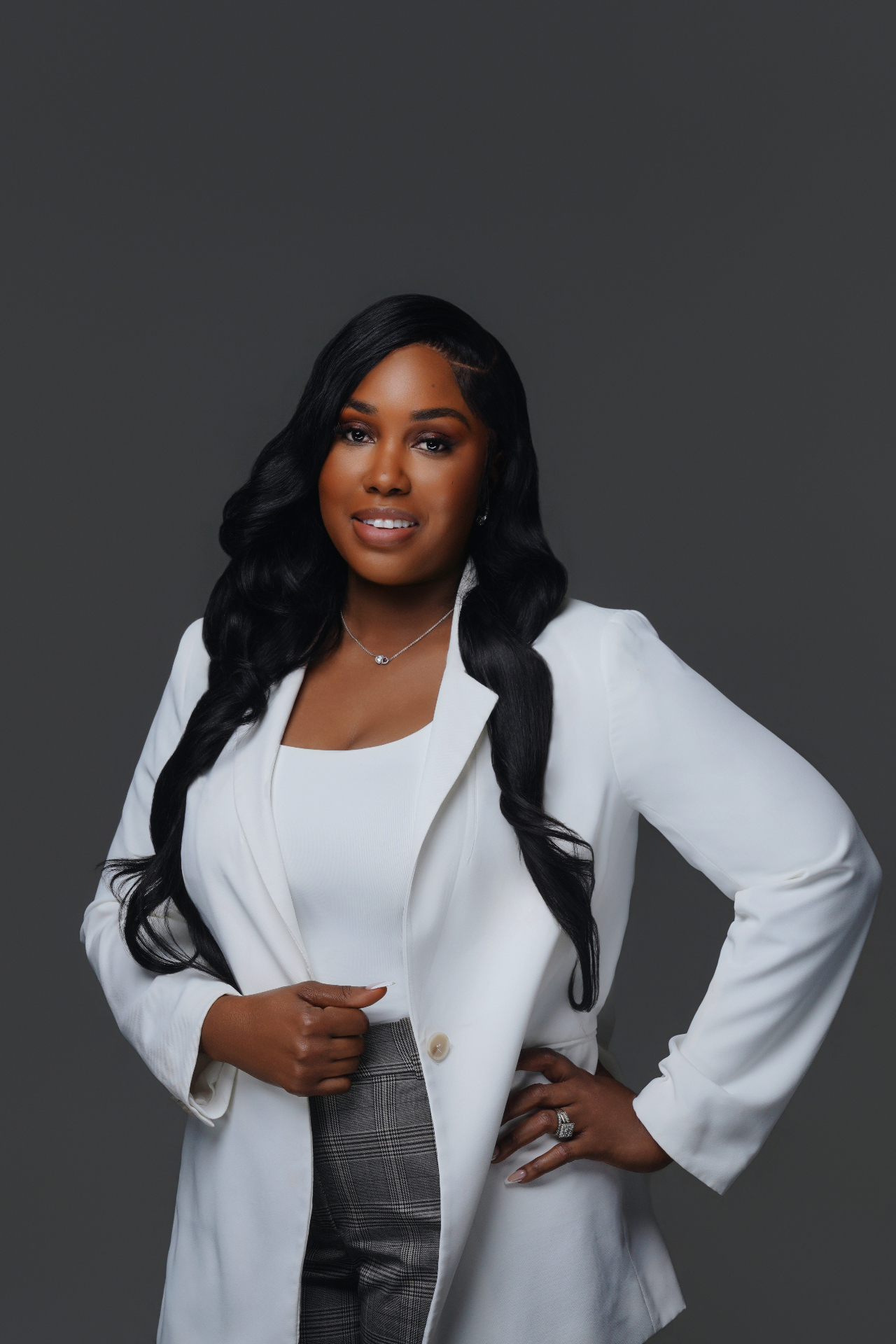 Professional branding portrait of a woman in a white blazer against a gray background